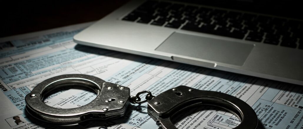 Handcuffs on top of fake tax documents and a laptop showing a romance scam chat window, representing the Thomas Addaquay fraud case.